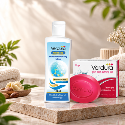 Verdura skincare set featuring a 100 ml bottle of Intense Moisturising Lotion, a 75 gm box of Skin Fresh Bathing Bar, and a pink oval bar of soap, styled on a marble slab with folded towels and botanical elements.